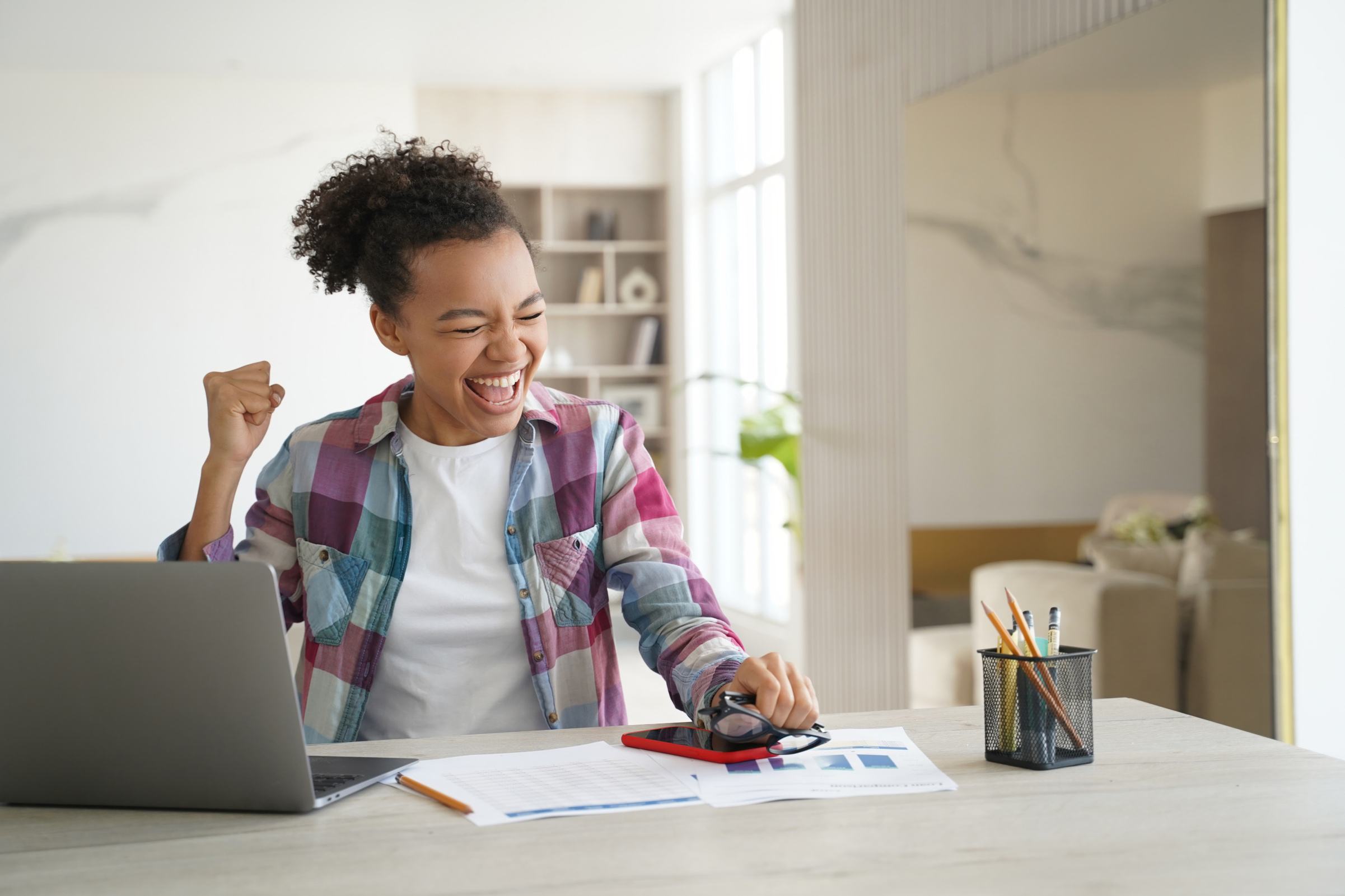 Joyful biracial teen student celebrates success with laptop emai